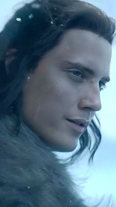 a close up of a person with long hair wearing a fur coat and looking off into the distance