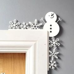 a snowman is hanging on the wall next to a frame with an ornament