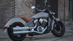 a silver motorcycle parked in front of a brick building