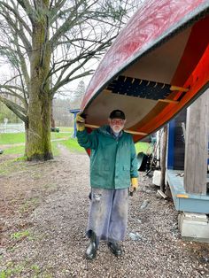 a man standing in front of a red canoe