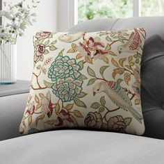 a decorative pillow on a couch in front of a window