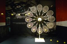 a clock made out of tennis rackets on display in front of a black background