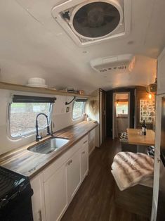 the interior of an rv with wood flooring and white cabinets, including a stove top oven