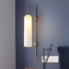 a wall light that is on the side of a blue wall next to a chair