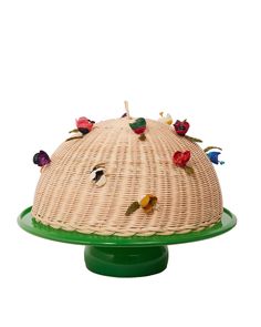 a wicker cake with flowers on top sitting on a green plate in front of a white background