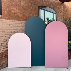 three different colored arches in front of a brick building with a window and planter