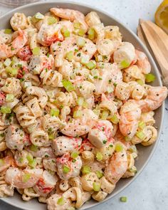 a bowl filled with pasta salad next to sliced lemons