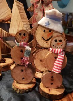 three snowmen made out of logs with hats and scarves