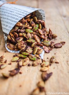 pistachio nuts spilling out of a bag on a wooden table with an open book in the background