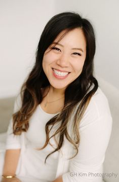 a smiling woman sitting on top of a white couch