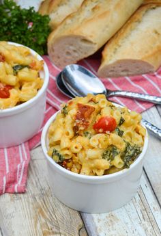 two white bowls filled with macaroni and cheese on top of a wooden table