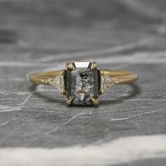 an engagement ring with a black and white diamond in the center, on a marble surface