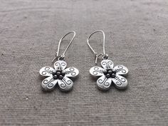 Here are some pretty and unique flower dangle earrings.  They are so sweet and would be perfect for everyday wear.  Theses earrings would also make the perfect little gift for someone special.  Made from allergy free plated silver.  They measure 5/8" across by 5/8" long and hang from 1" kidney style ear wires.  Overall length is 1 5/8" long.I have a matching necklace in my store if you would like the whole set.  Here is a direct link........... https://etsy.me/317bnO3 Thanks for stopping by!  Pl Whimsical Spring Flower Earrings With Ear Wire, Whimsical Spring Earrings With Flower Charm, Whimsical Adjustable Flower Charm Earrings, Bohemian Silver Flower Earrings, Silver Bohemian Flower Earrings, Whimsical Flower Charm Earrings, Whimsical Flower-shaped Earrings With Flower Charm, Bohemian Hypoallergenic Flower Earrings, Bohemian Flower Charm Drop Earrings