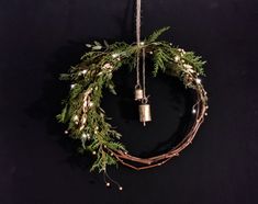 a christmas wreath with bells hanging from it's side on a black wall background