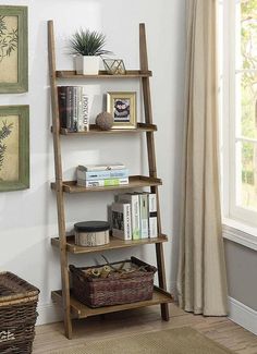 a wooden ladder shelf with books and other items on it next to a window in a living room