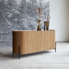 two vases sitting on top of a wooden cabinet in front of a wall mural