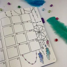 a calendar with feathers and beads on the cover, next to a feather quill pen