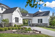 a large white house with lots of windows and landscaping around it's front yard