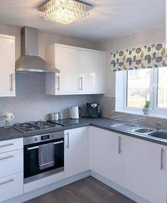 a kitchen with white cabinets and gray counter tops, silver appliances and a chandelier above the stove