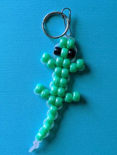 a keychain made to look like a lizard with black eyes and green beads