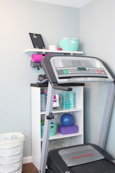 a treadmill in the corner of a room next to a shelf with items on it