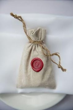 a bag with a wax seal on it sitting on top of a white table cloth