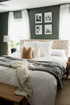 a bed with pillows and blankets on top of it in front of two framed pictures