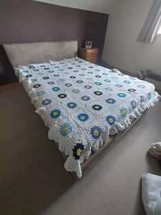 a crocheted blanket on top of a bed in a room with a window