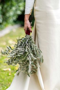 a woman in white dress holding a bunch of olives on her hand and wearing red shoes