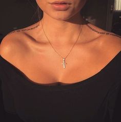 a woman wearing a black shirt with a cross tattoo on her chest and necklace around her neck