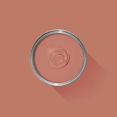 a pink paint can with a long shadow on the wall in front of an orange background