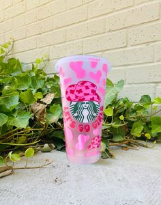 a pink starbucks cup sitting on top of a sidewalk