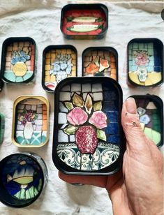 a person holding up a small box with stained glass designs on it's sides