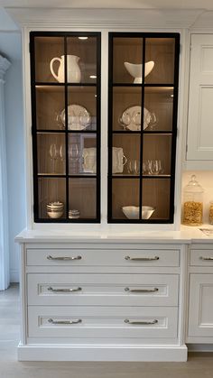 a kitchen with white cabinets and black glass front cupboards on the countertop,