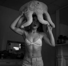 a woman is holding an octopus stuffed animal over her head while standing in a room