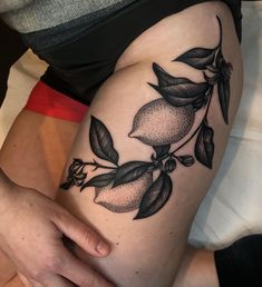 a woman's thigh with an orange and leaves tattoo on it