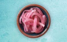 a wooden bowl filled with sliced onions on top of a blue table