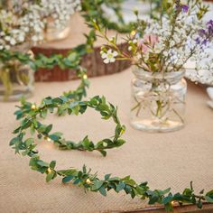 flowers and greenery are arranged in vases on a table