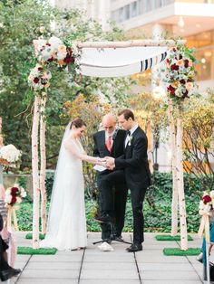 a bride and groom are getting married under an outdoor wedding ceremony arch with flowers on it