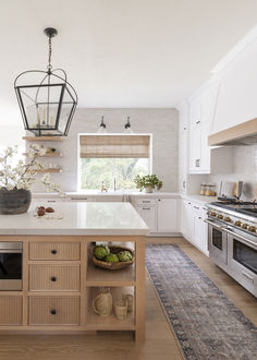 a kitchen with white cabinets and an island in front of a stove top oven next to a window