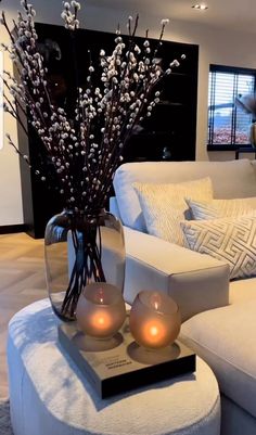 a living room with white furniture and candles on the coffee table in front of it