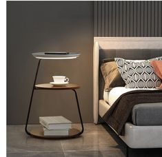 a bed sitting next to a night stand with a cup on it's side