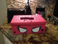 a pink box with eyes painted on it sitting on top of a counter next to a blender