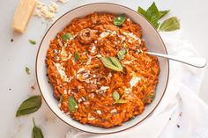 a white bowl filled with pasta and garnished with herbs