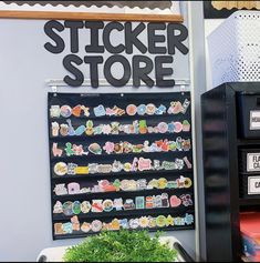 a black sticker store sign sitting on top of a wall next to a potted plant