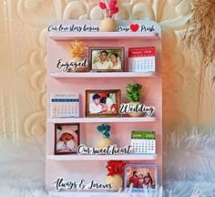 a pink shelf with pictures and calendars attached to the sides, sitting on a white furnishing