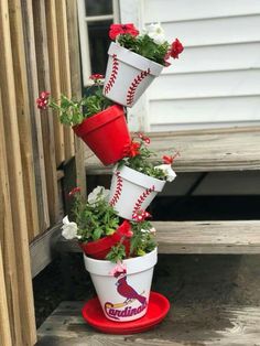 three red and white buckets filled with flowers sitting on top of a wooden porch