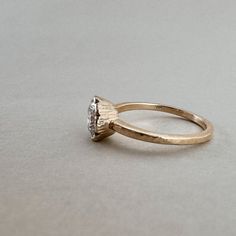 an engagement ring with a single diamond in the center on a plain surface, ready to be worn