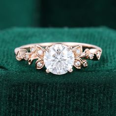 an engagement ring is shown on top of a green velvet cushion with diamonds around it