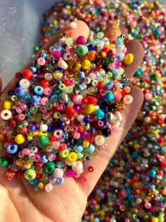 a hand holding a bunch of beads in it's palm, with lots of them scattered around